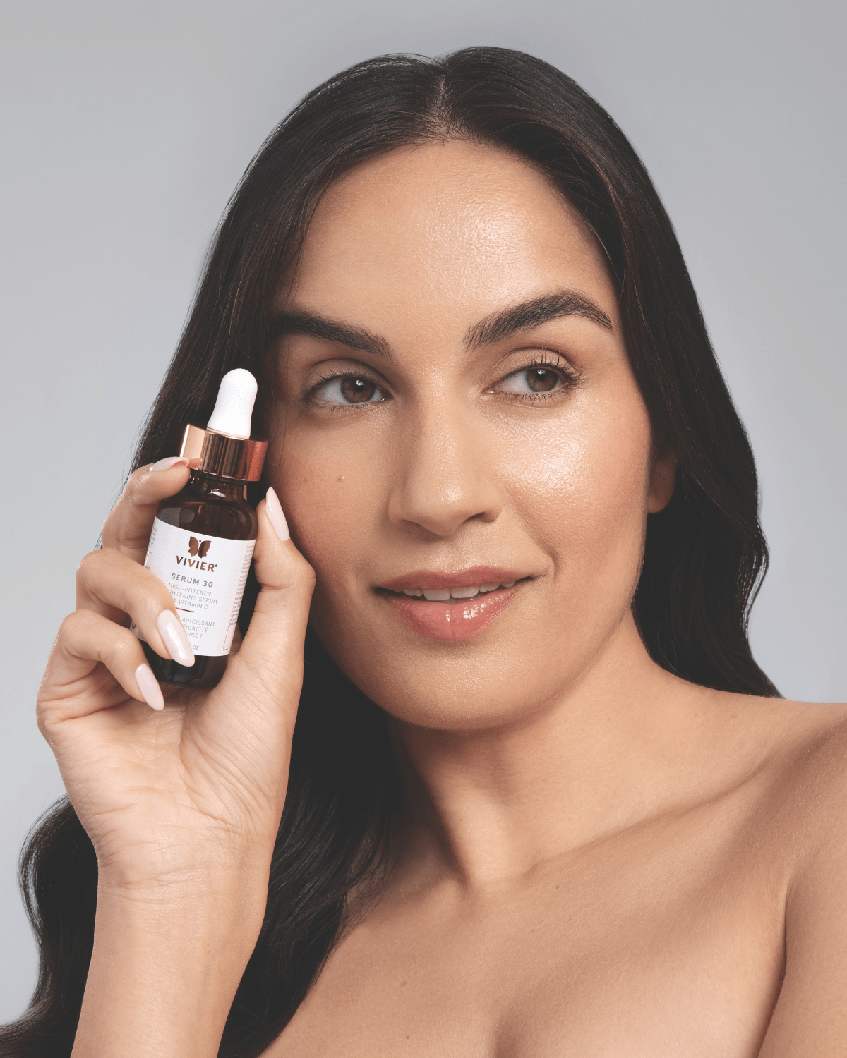 Woman holding a bottle of Serum 30 -Targets both surface-level and deep pigmentation and damage