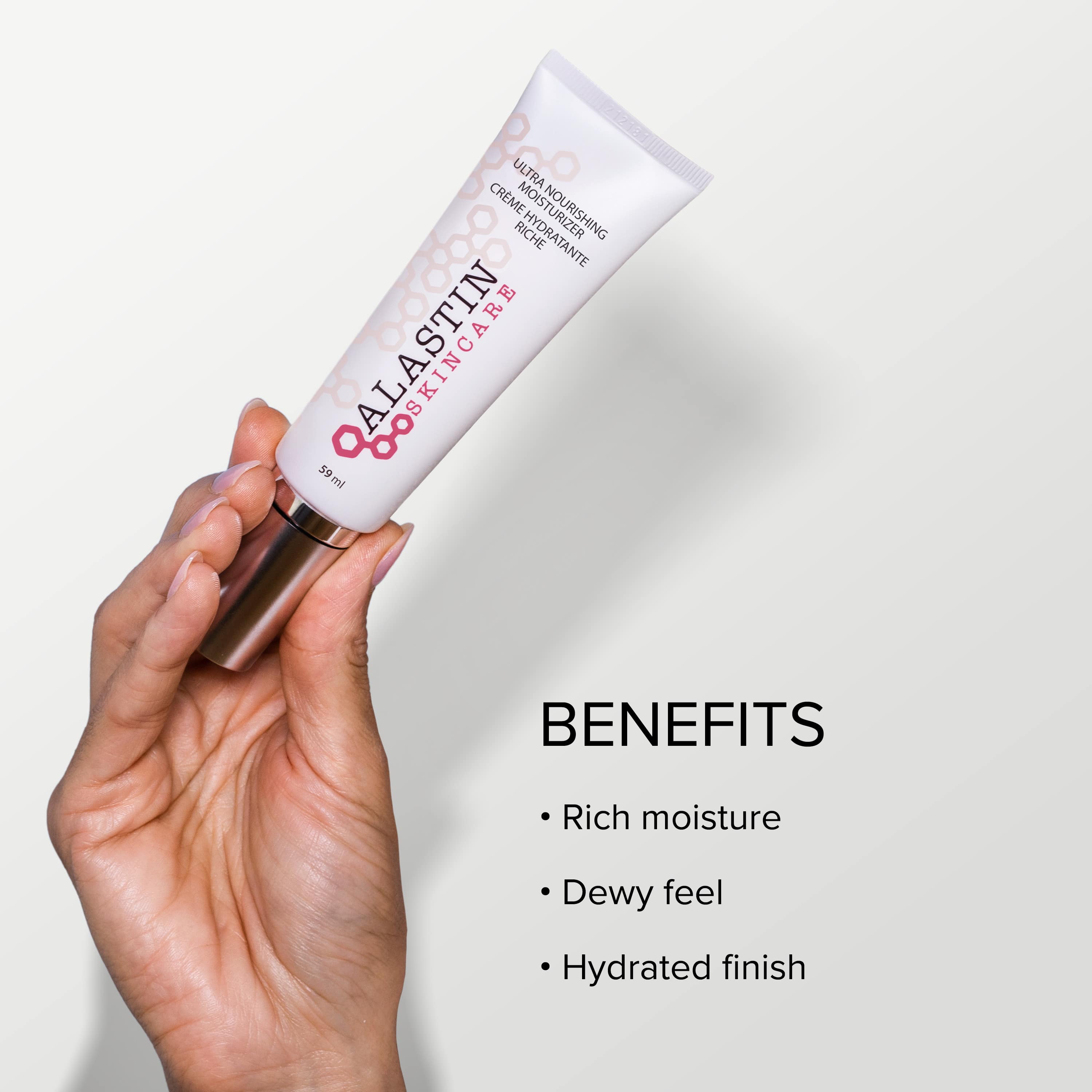 Hand holding a tube of Alastin Skincare cream with benefits listed on a light background - Rich moisture, dewy feel, hydrated finish