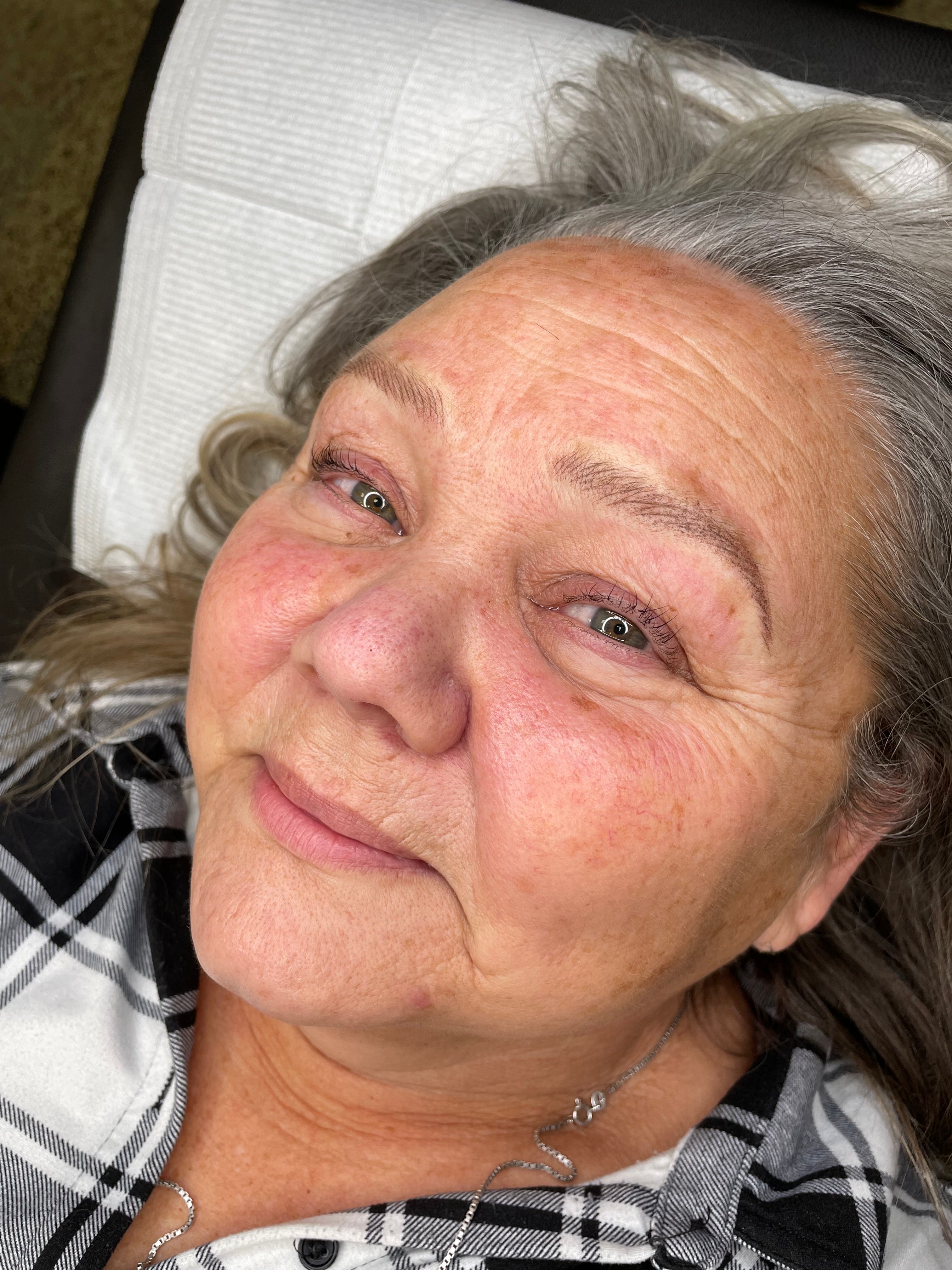 A close-up lifestyle shot of an older woman lying down, after getting Nano Brows - 