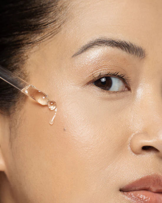 Close-up of a woman's face with a dropper applying Serum 10 to her skin to  helps reduce the appearance of fine lines and early aging concerns